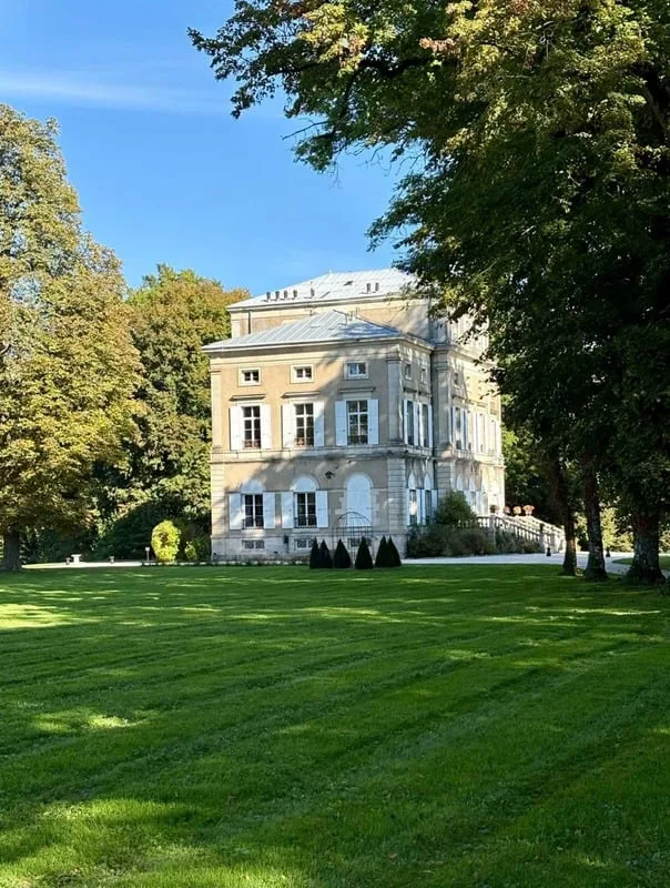 Château de Trouhans across its lawn, under tall trees